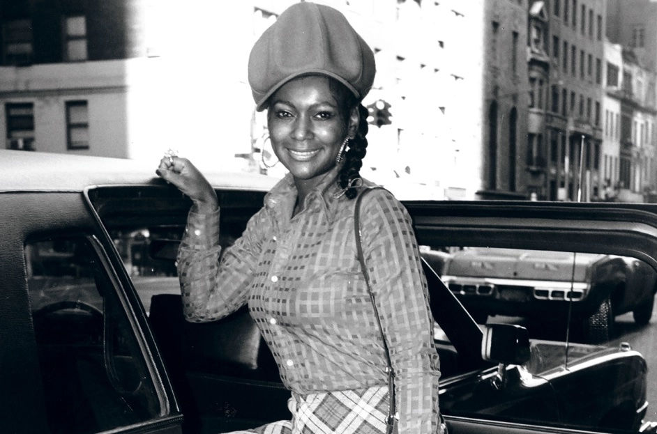 Photo of a black woman in the late 1970s with stylish outfit on and hoop earrings