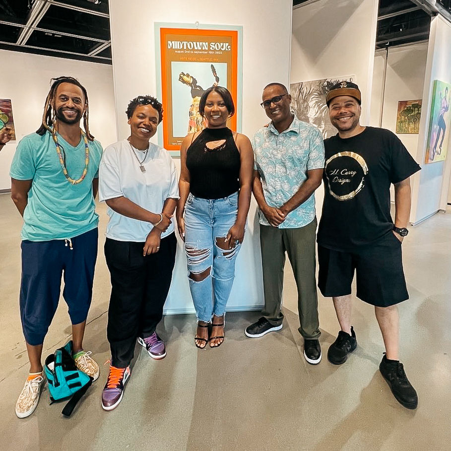 Five men and women stand in front of an art gallery exhibit
