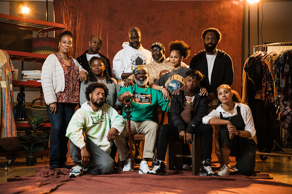 A multi-generational cast of Black actors poses together in the dressing room of a theatre