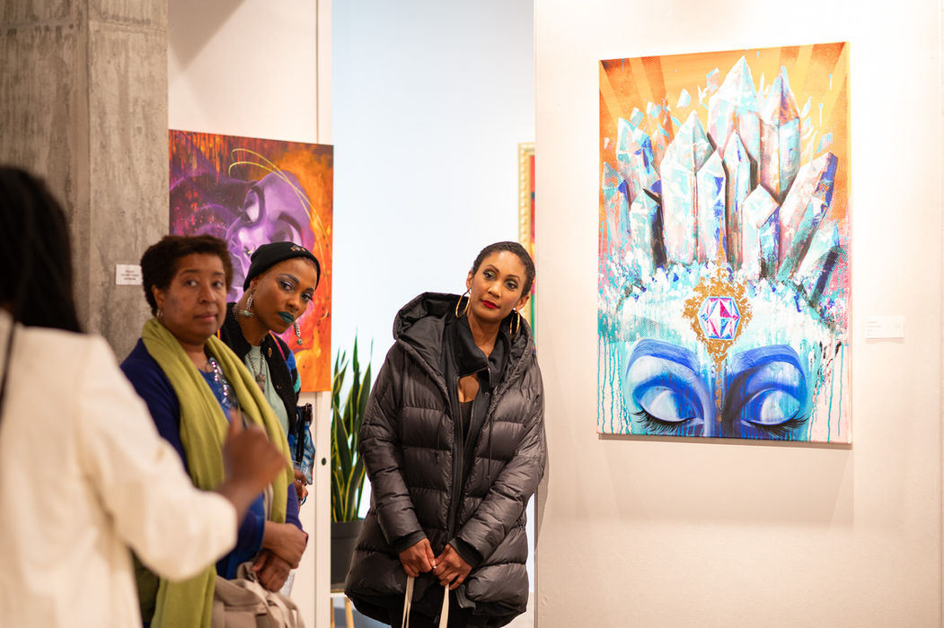 Art gallery attendees view vibrant paintings