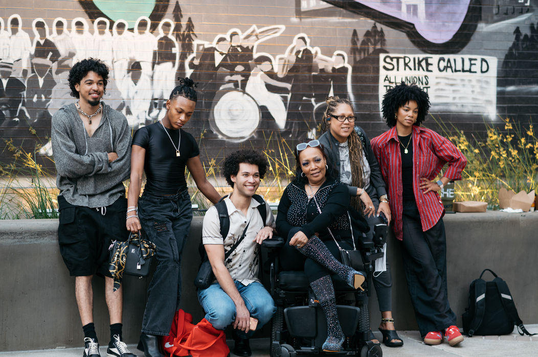 Group portrait: diverse models pose near mural