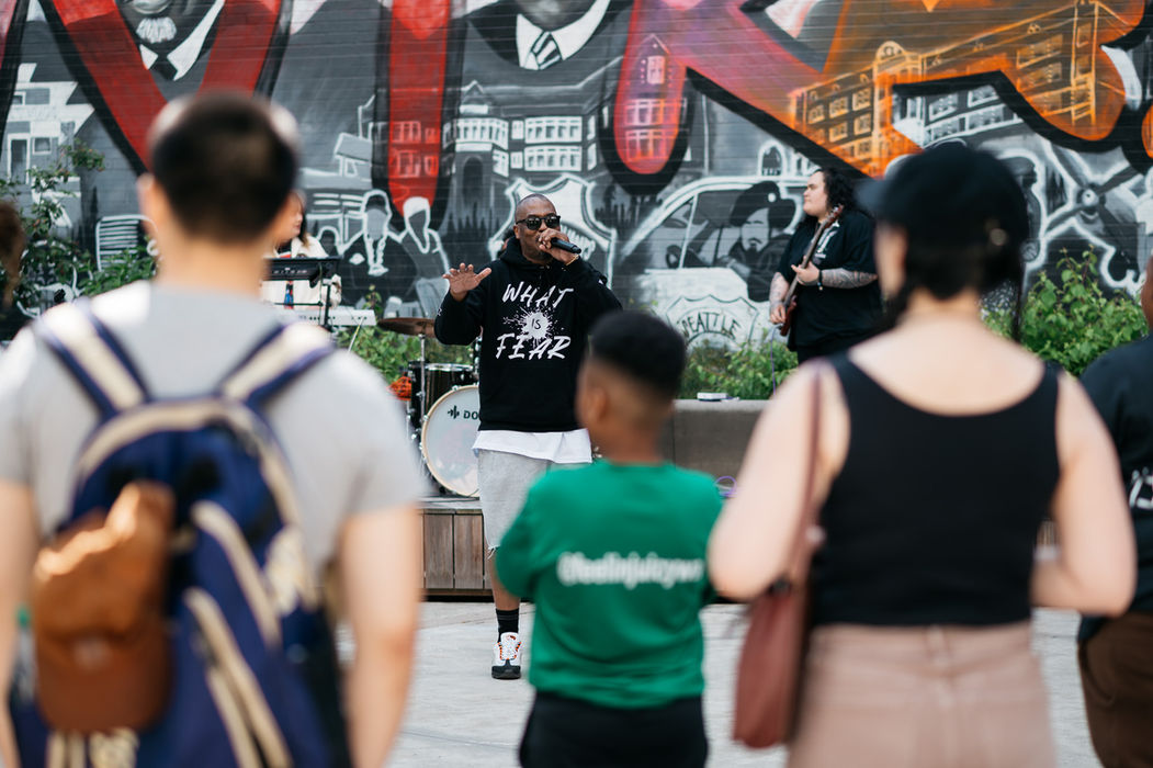 Man rapping with audience before mural