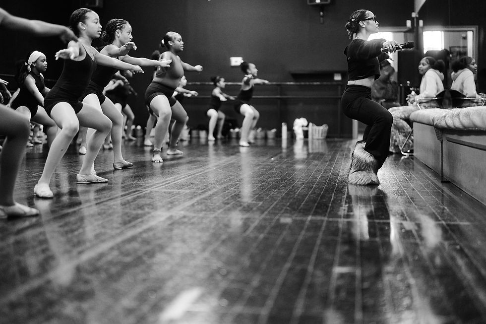 An instructor leads a seated group of dancers through an exercise at AREA Atlanta.