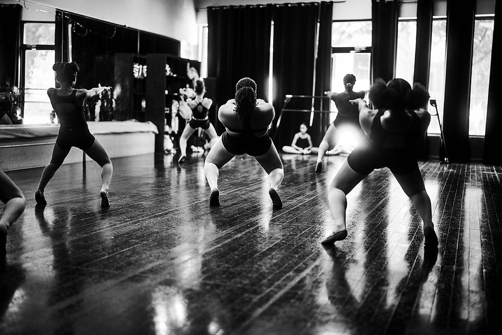 Dancers move across the studio floor, their shadows extending through the frame.