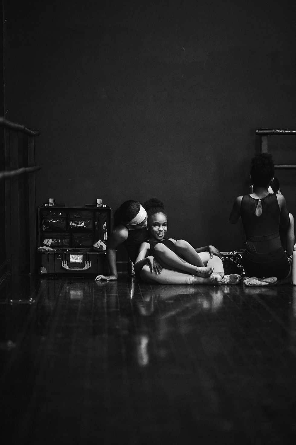Dancers share a moment together beside their belongings in the studio.