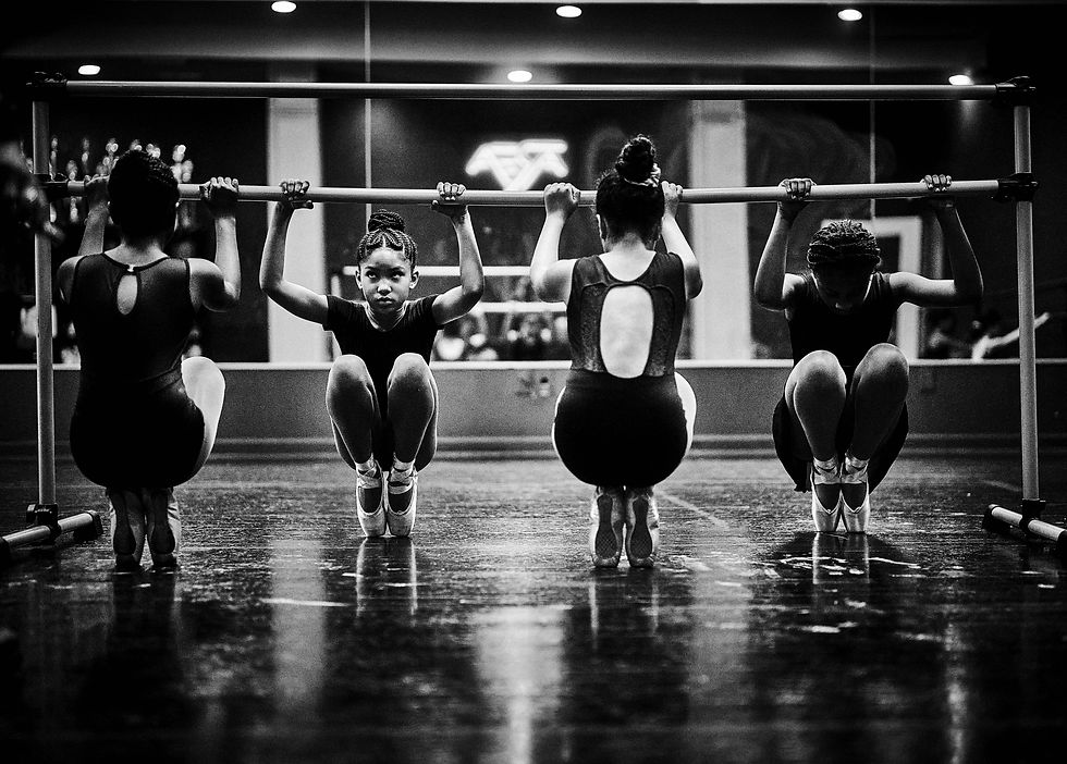 Four young dancers practice an exercise at the barre.